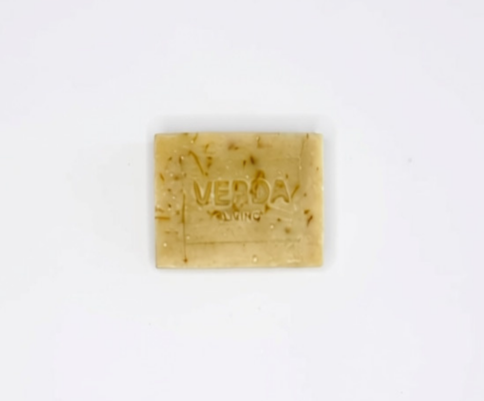 A rectangular bar of citrus VERDA LIVNG soap, featuring a pale orange color with visible brown calendula petals, centered on a plain white background.