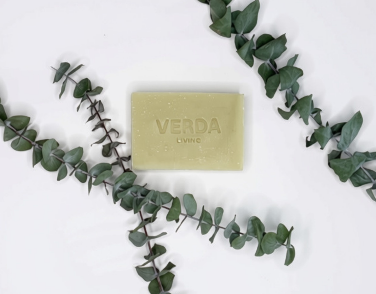 A rectangular bar of VERDA Living soap in a pale green color, embossed with the brand name, styled on a white background with green eucalyptus branches.