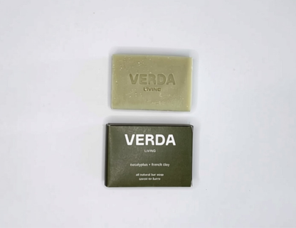 A bar of VERDA LIVING eucalyptus soap on a plain white background, with it's green box packaging underneath. 